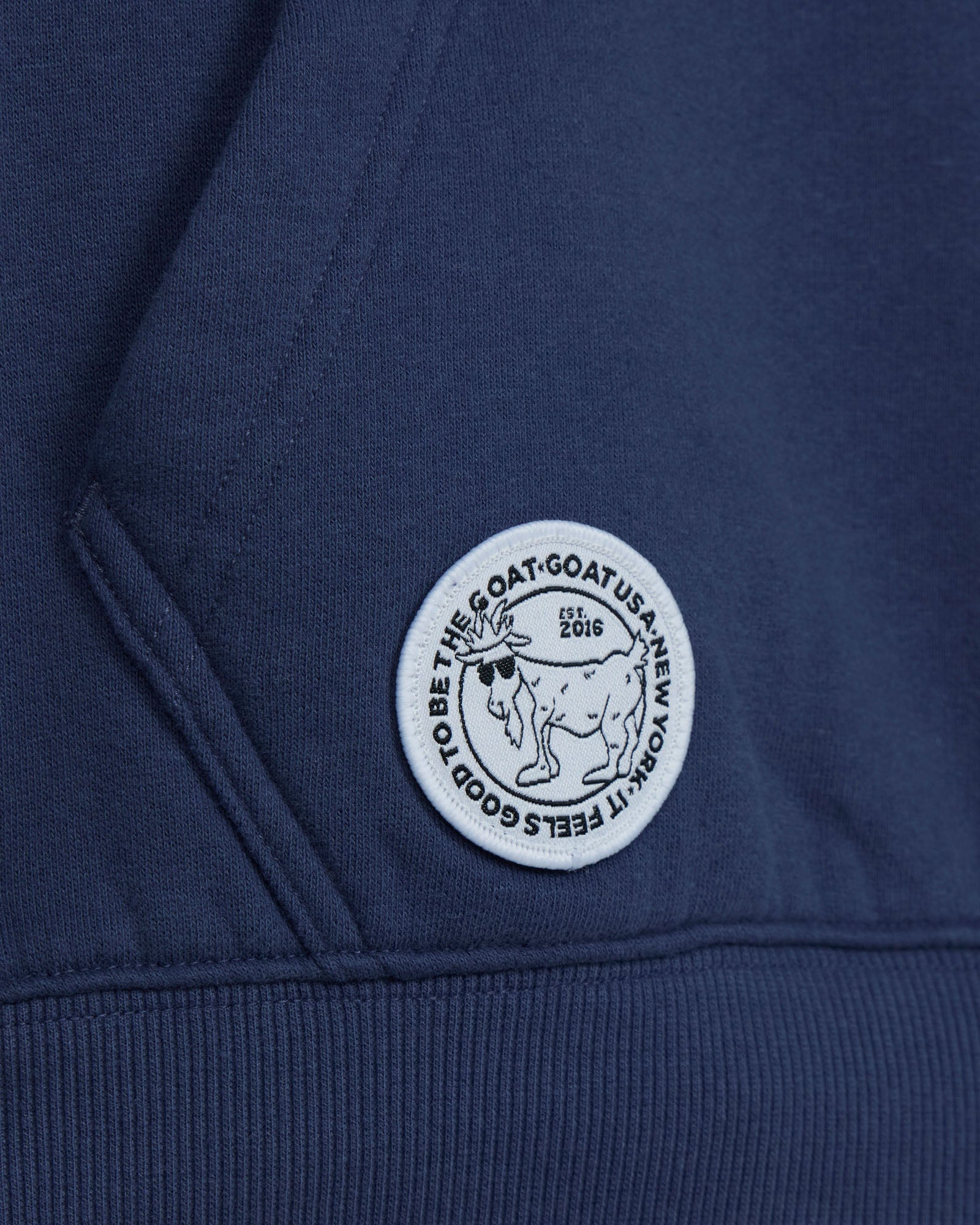 Close-up of a blue hoodie with a white logo on a dark background