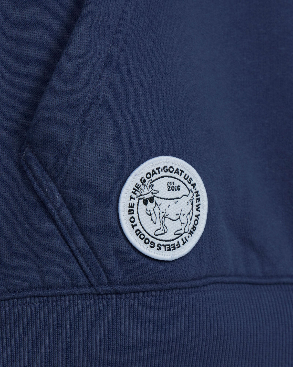 Close-up of a blue hoodie with a white logo on a dark background