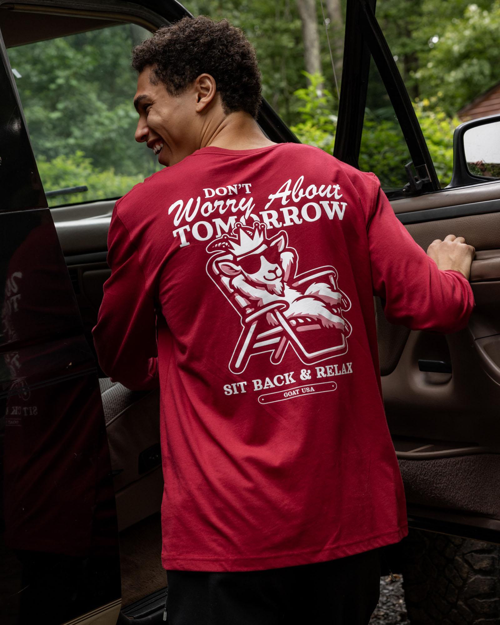 Person wearing a red t-shirt with a graphic and text, standing next to a vehicle.