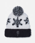 A knit pom-pom beanie hat featuring a white faux-fur upper section with black snowflake patterns, a black ribbed cuff, and a black-and-white pom-pom on top.