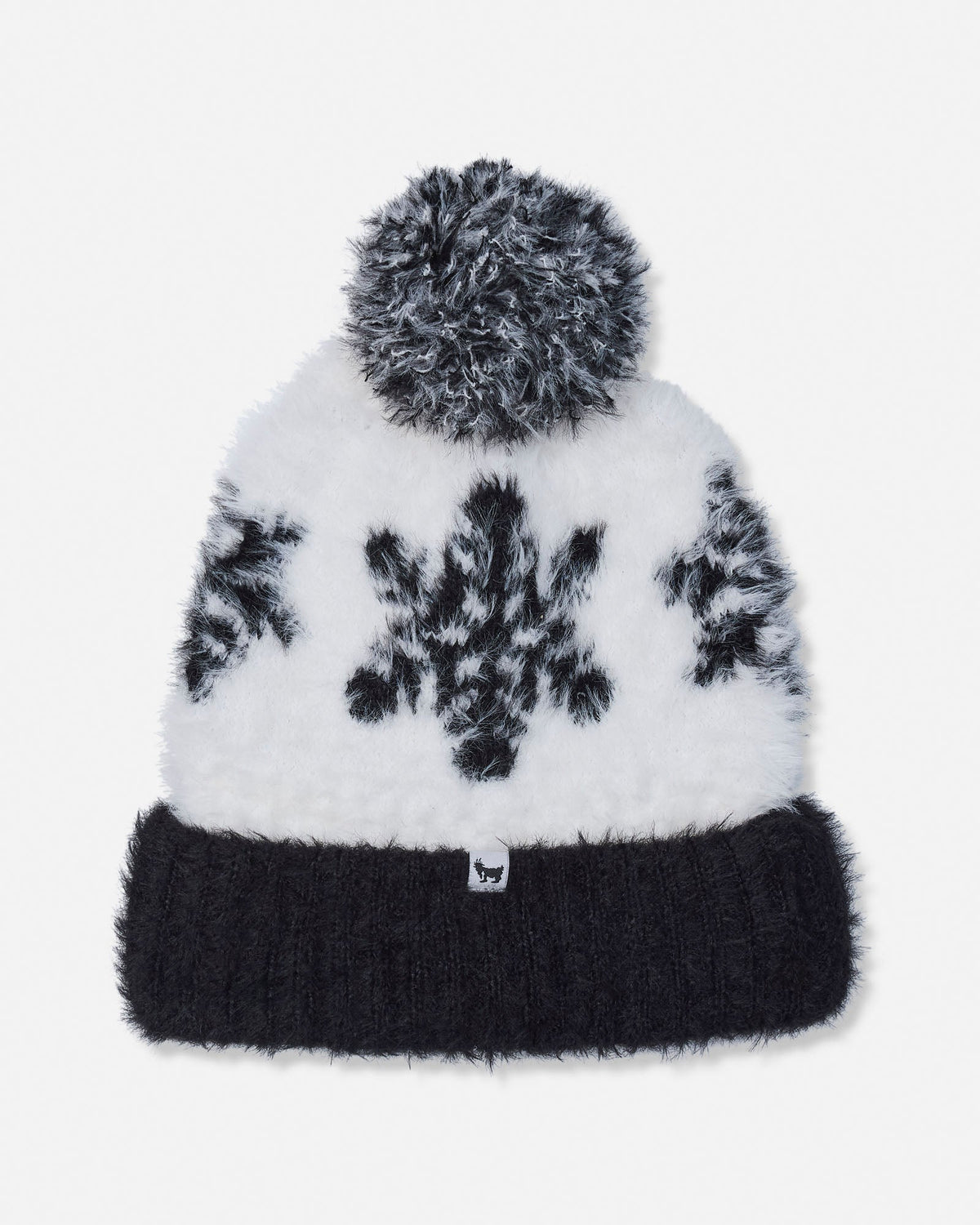 A white and black fuzzy knit beanie with a black pom-pom and a black ribbed cuff, featuring a black snowflake pattern and a small white logo tab on the front.