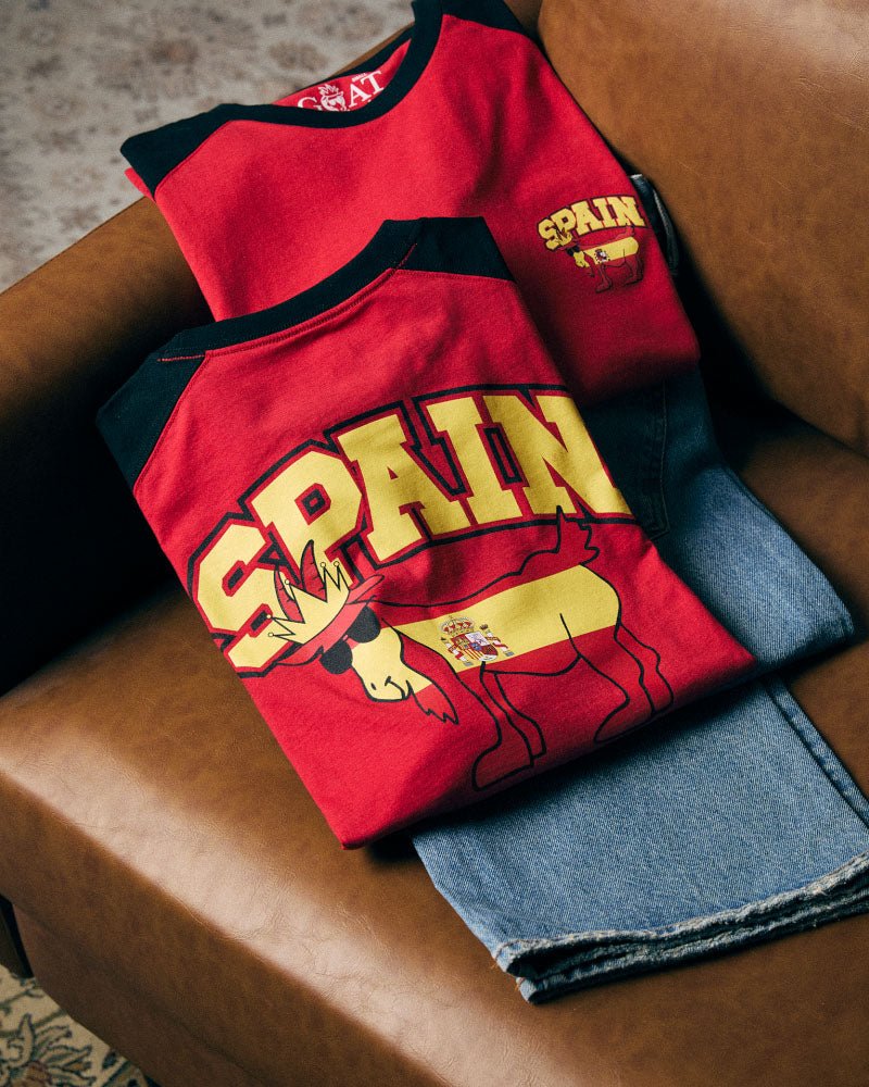 Red shirt with 'Spain' and goat design on a brown surface