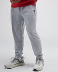 Person wearing gray jogger pants with a red top and white sneakers on a light gray background