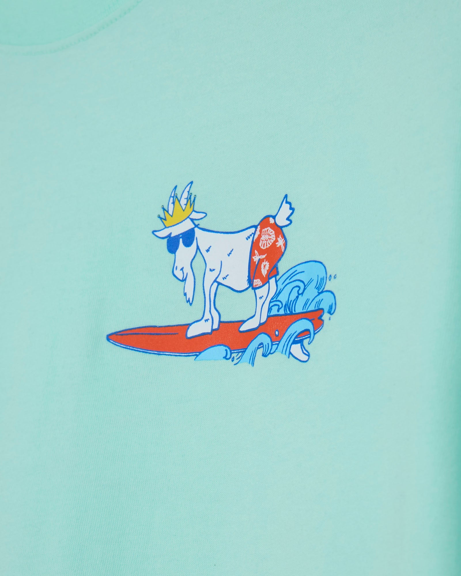 Illustration of a goat with a crown surfing on a wave, on a mint background.