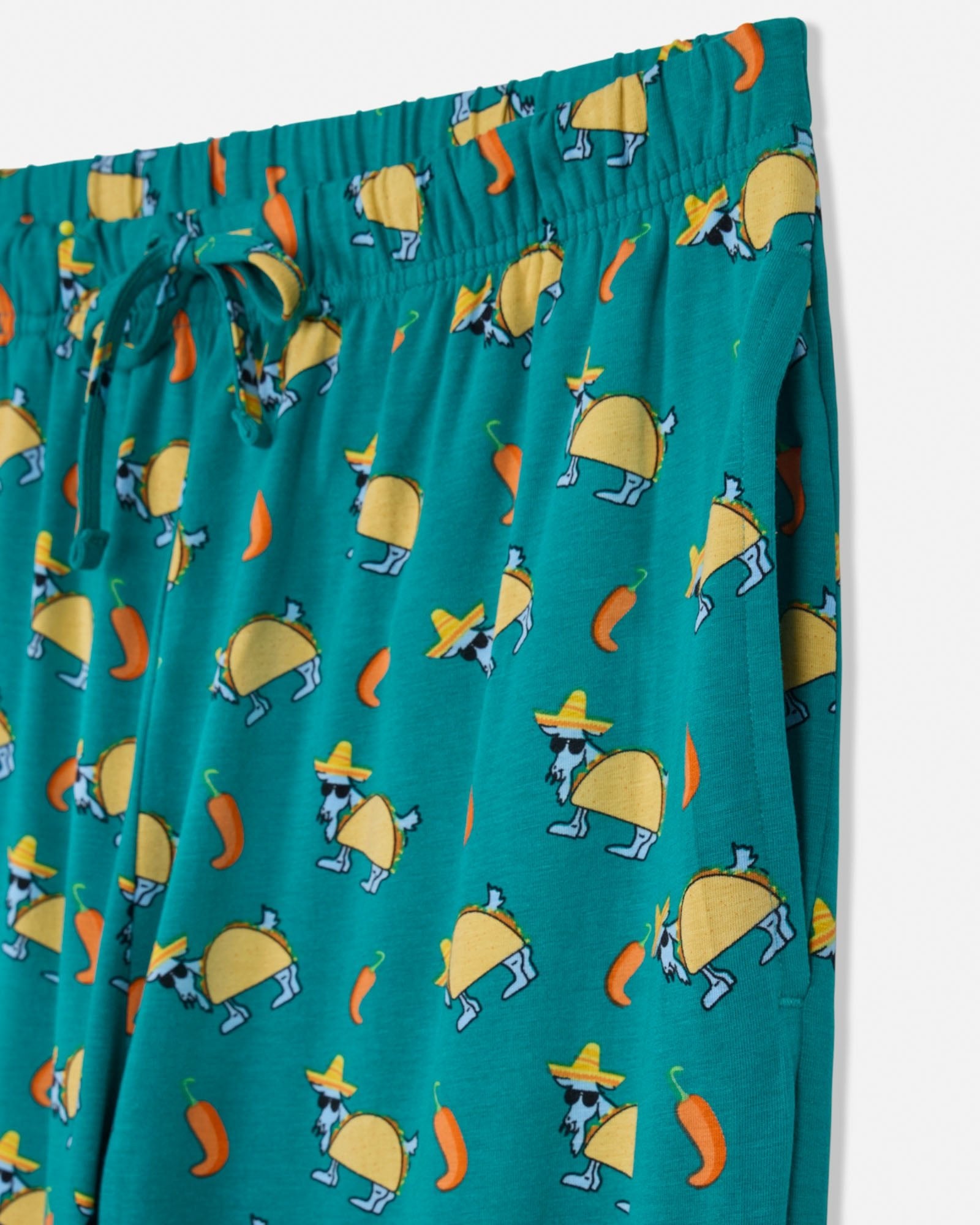 Teal pajama pants with taco pattern on a white background