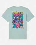 A light mint green crewneck t-shirt with a colorful graphic on the front that reads 'APRÈS-SKI CREW' above an illustration of a cartoon character skiing in front of mountains.