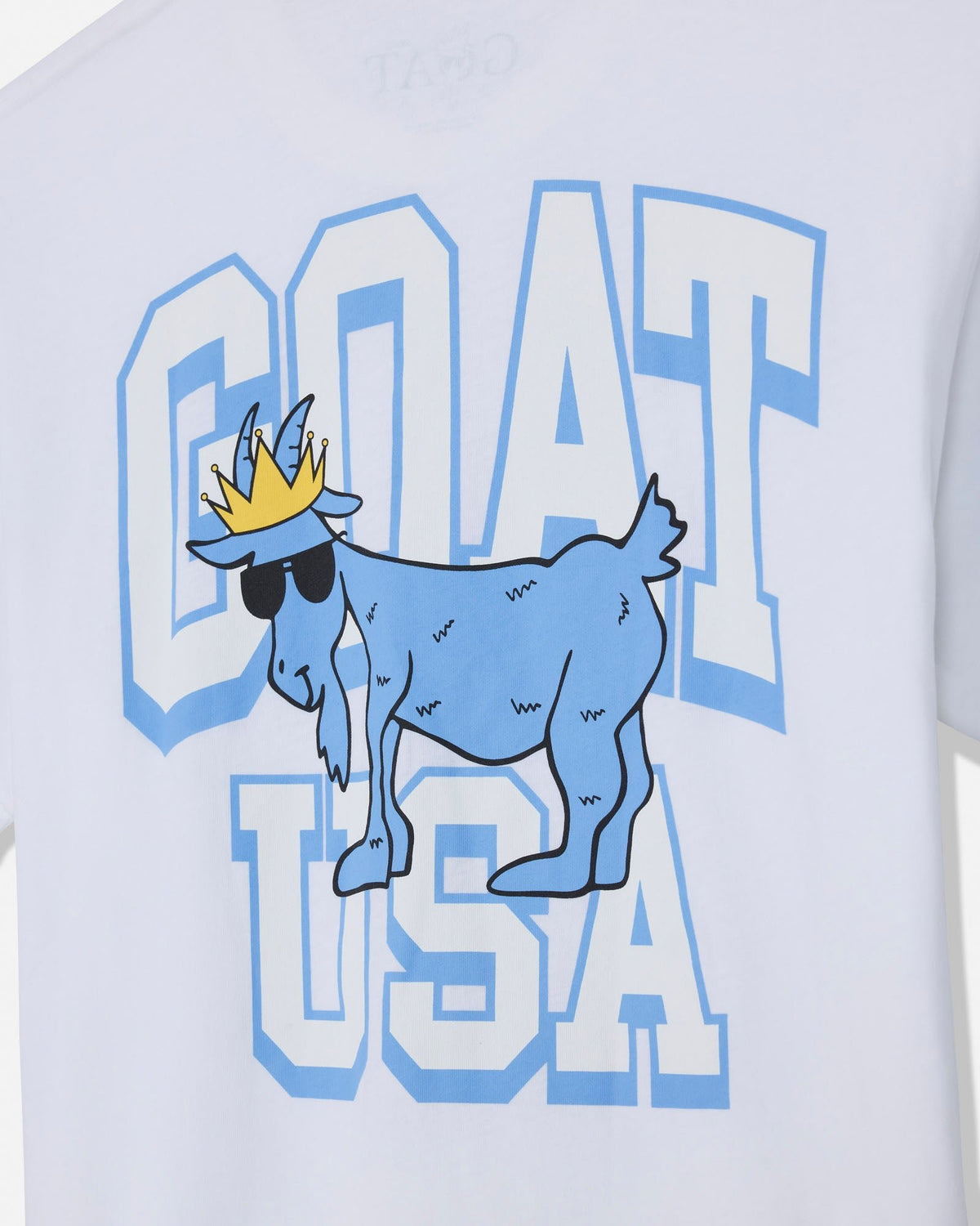 White t-shirt featuring a graphic print of a blue cartoon goat wearing a gold crown and black sunglasses, set against large varsity-style block letters spelling 'GOAT USA'.