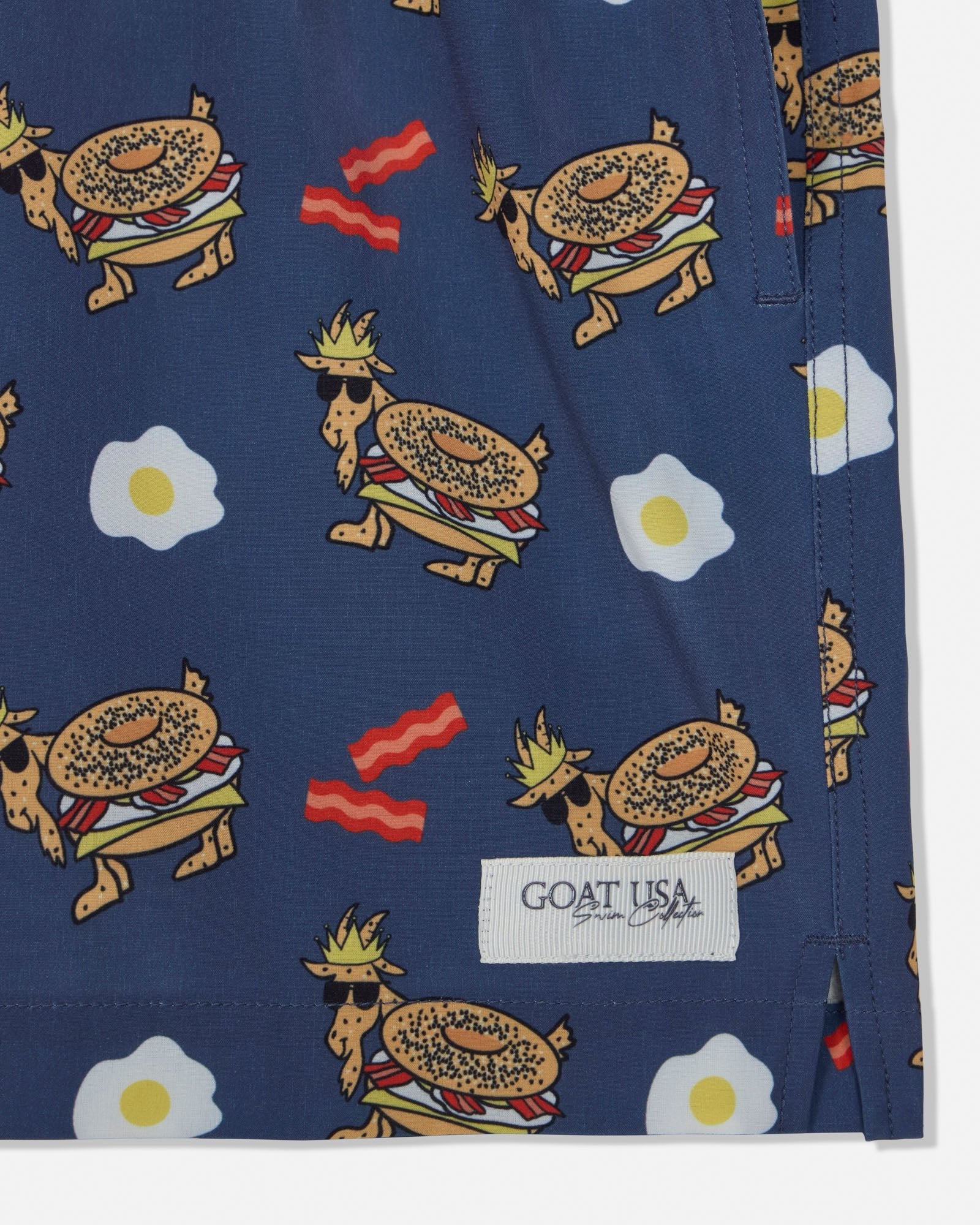 Navy shorts with a colorful pattern of bagels, eggs, and bacon on a white background.