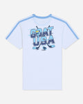 A white short-sleeve t-shirt with light blue shoulder stripes and a large 'GOAT USA' graphic printed on the chest in blue, navy, and yellow, set against a light gray background.