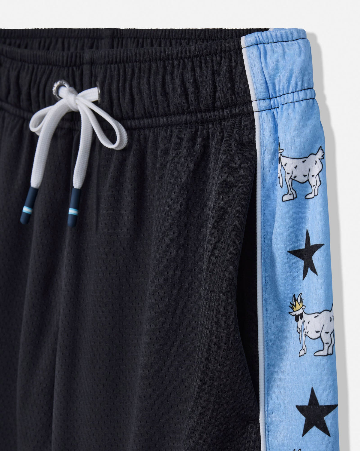 Close-up of black mesh athletic shorts with a light blue side stripe featuring cartoon goat and star graphics, plus a white drawstring.