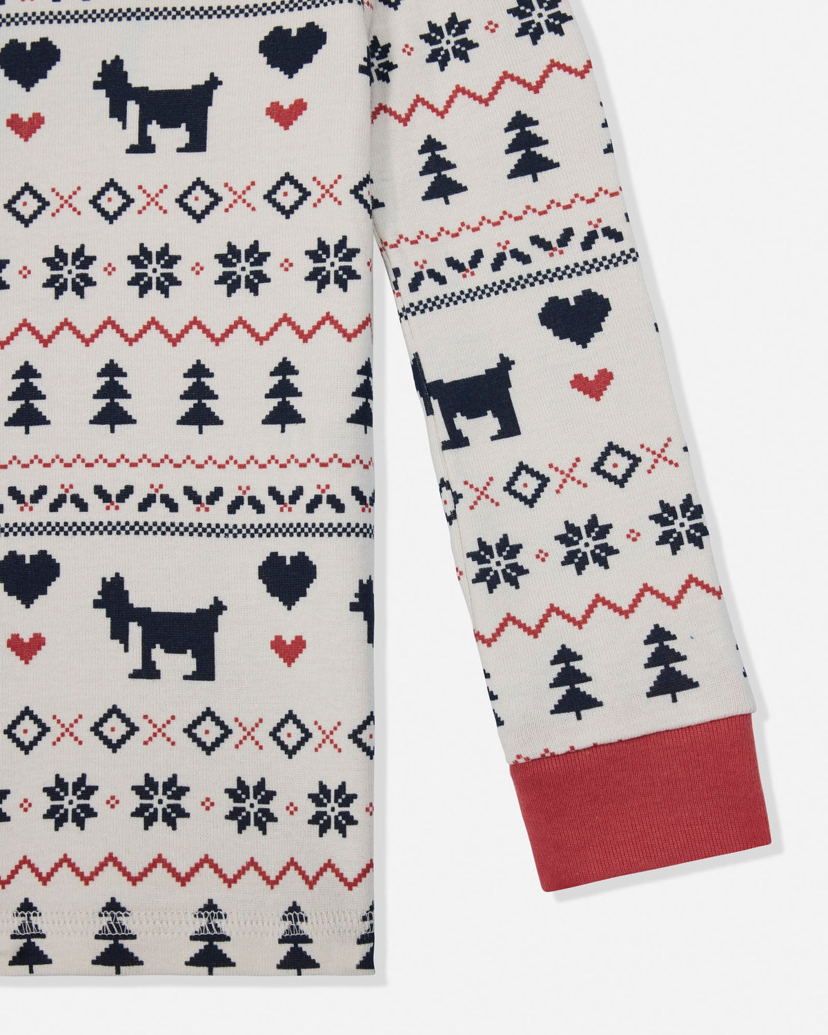 A close-up of a knit sweater or scarf with a festive holiday pattern featuring black goats, red hearts, navy trees, and geometric motifs on an off-white background, with a solid red cuff.