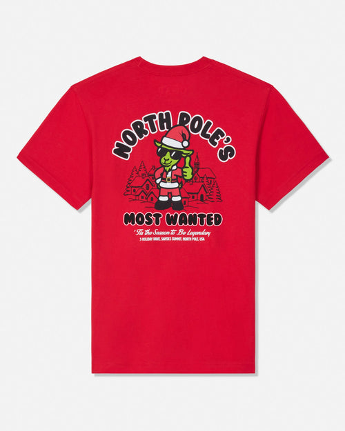 Red t-shirt with green santa cartoon goat character with text that reads "North Pole's Most Wanted"