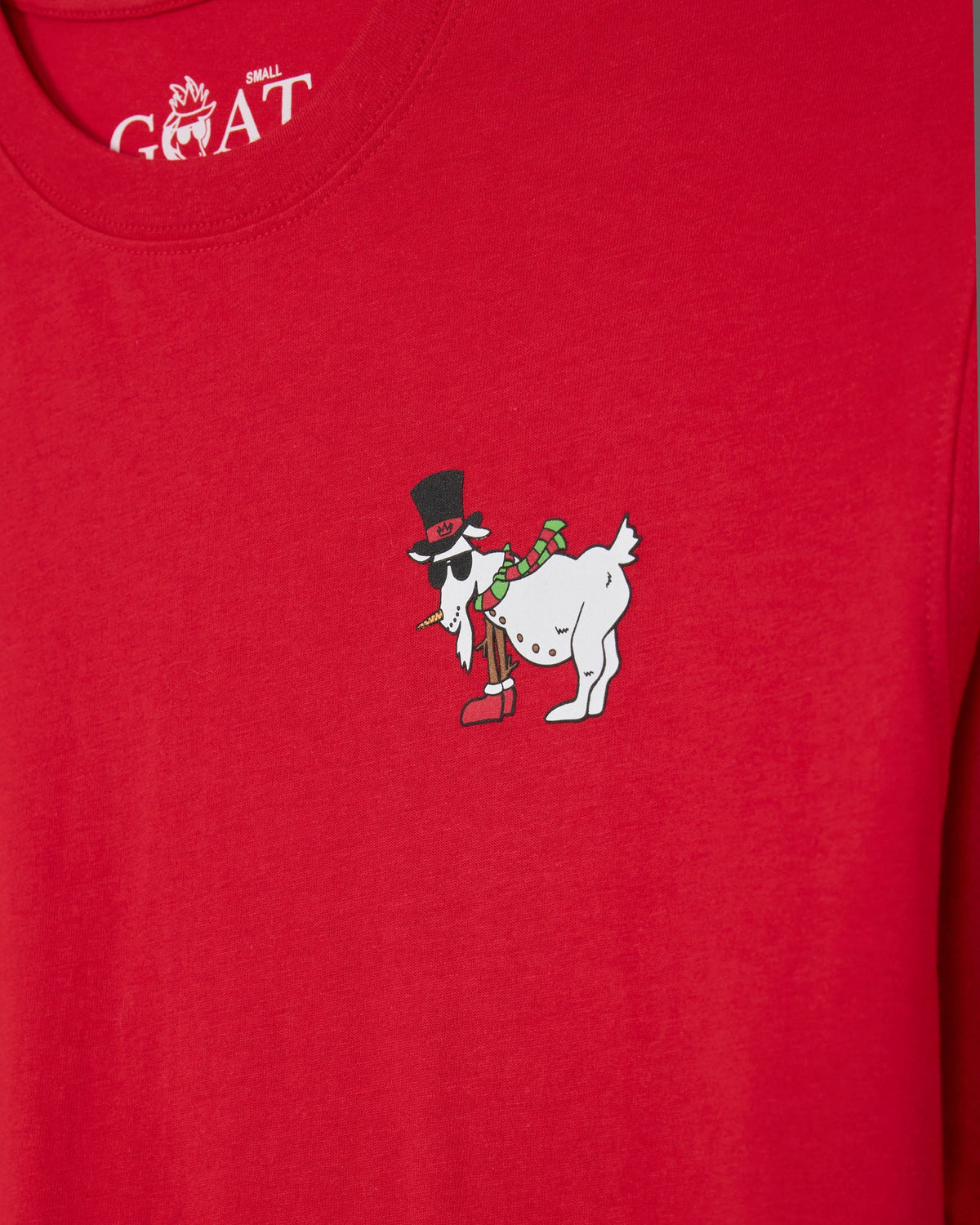 A close-up of a bright red t-shirt featuring a small graphic on the chest of a white goat wearing a black top hat and sunglasses, with a person riding it. The inside collar shows the white printed brand name 'GOAT'.