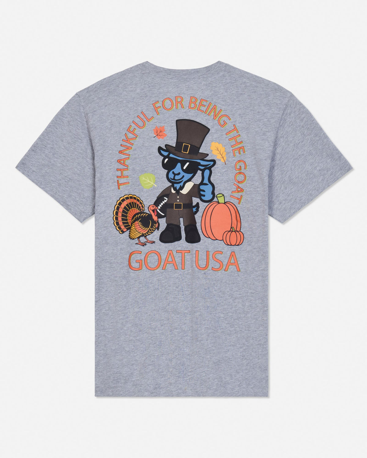 A heather gray short-sleeve t-shirt shown from the back, featuring a colorful graphic of a blue goat dressed as a pilgrim with pumpkins, a turkey, and autumn leaves, with the text 'THANKFUL FOR BEING THE GOAT' and 'GOATUSA'.
