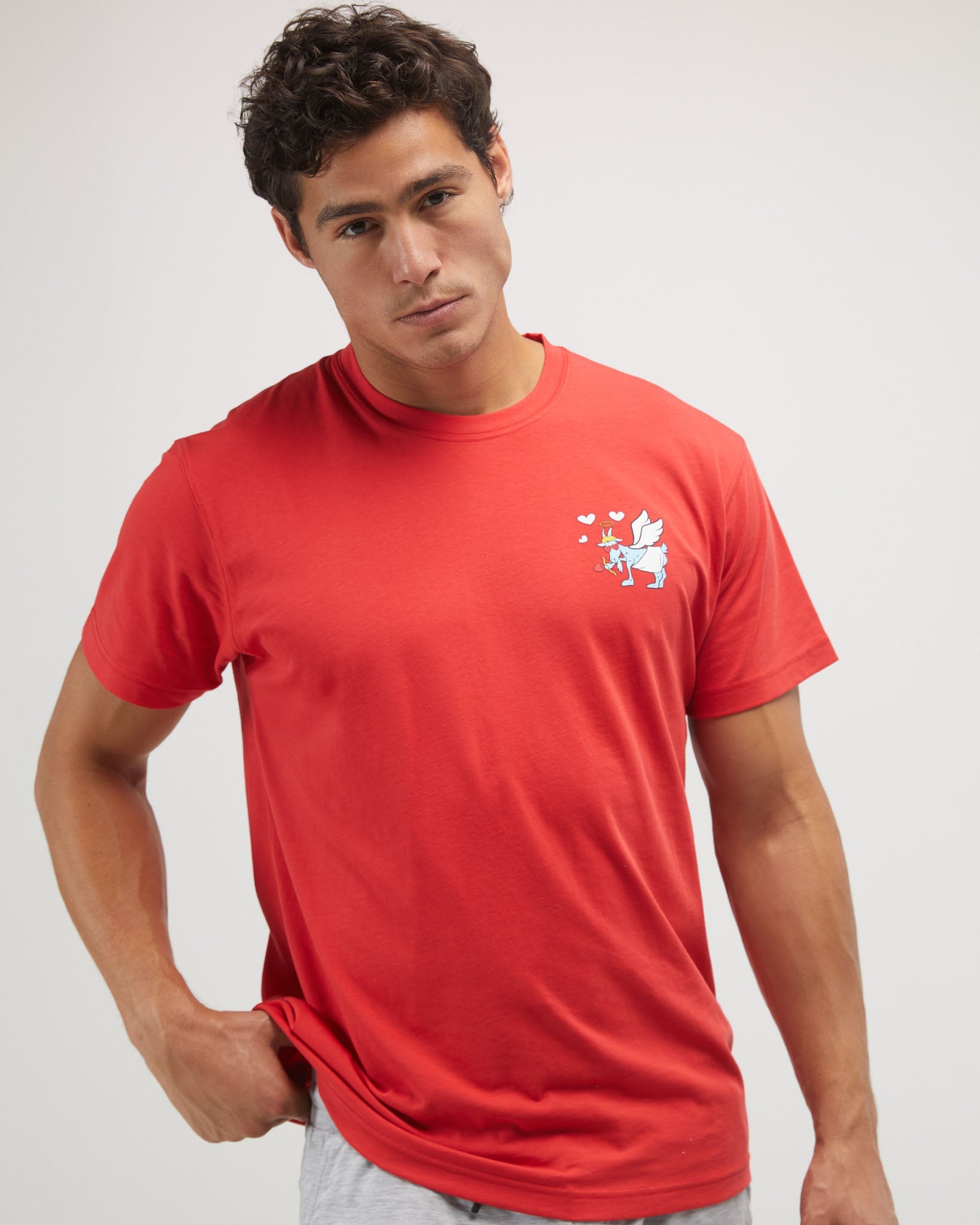 Man wearing a red t-shirt with a small white graphic on a light gray background