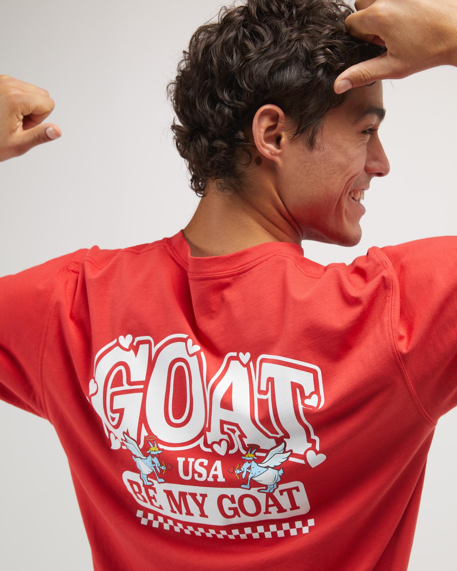 Person wearing a red shirt with 'GOAT USA' text on the back, posing against a plain background.