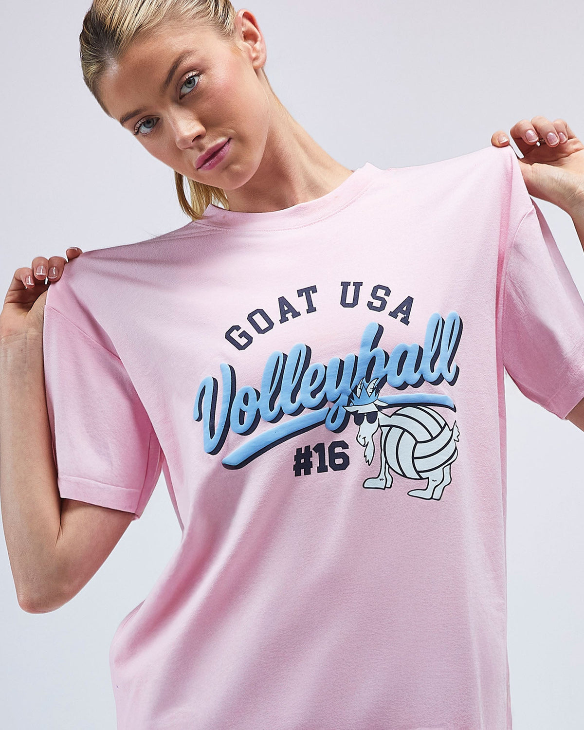 Woman wearing a pink t-shirt with 'GOAT USA Volleyball #16' text and graphics.