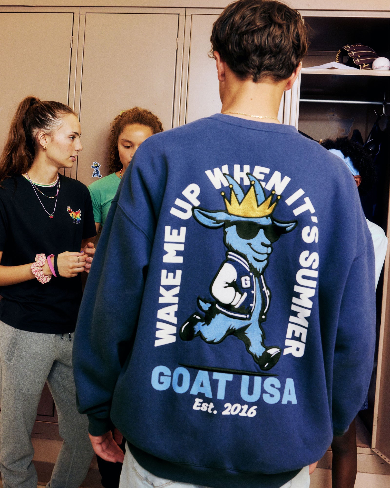 Person wearing a blue sweatshirt with a graphic and text, standing in a casual school setting.