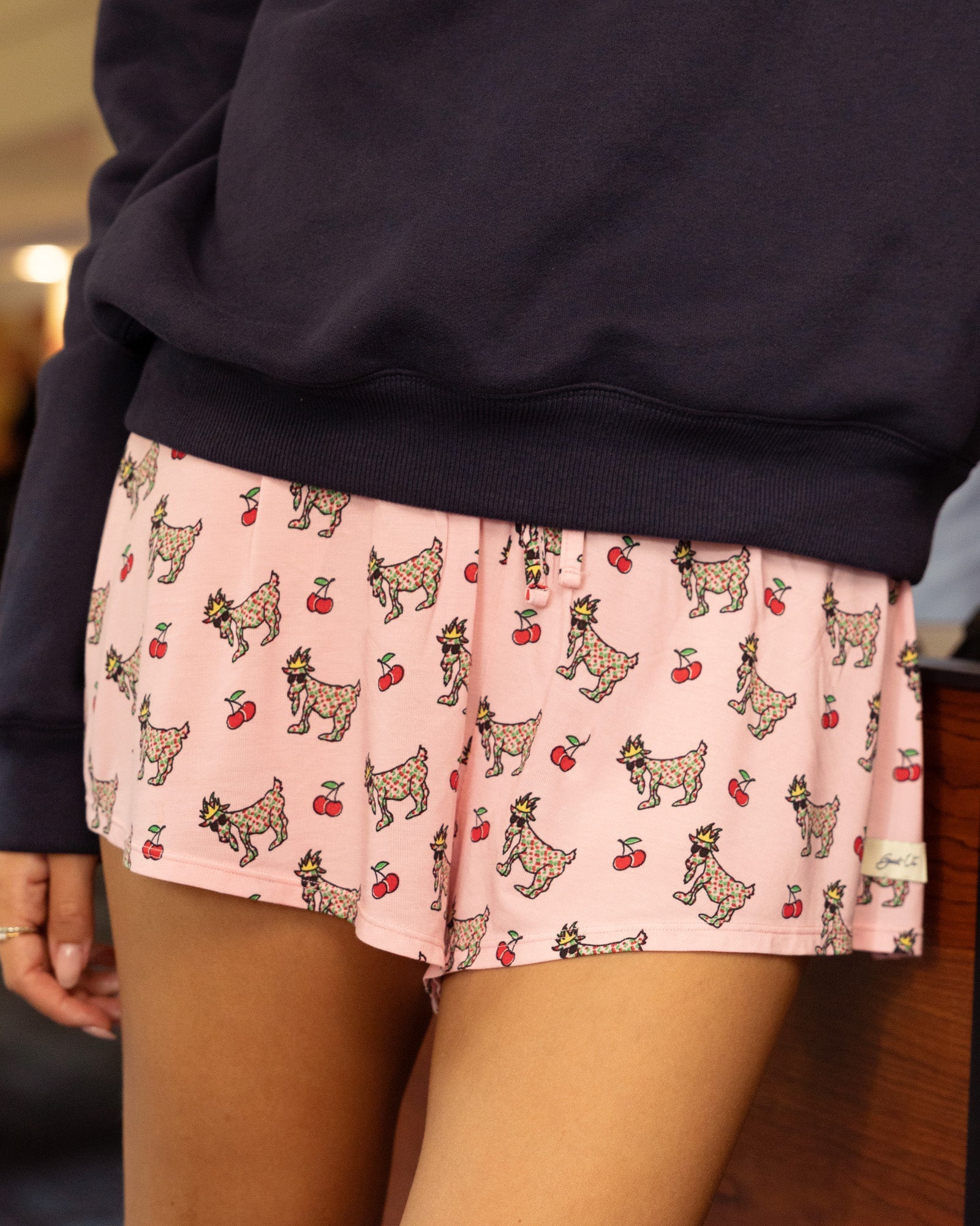 Person wearing pink shorts with goat and cherry pattern