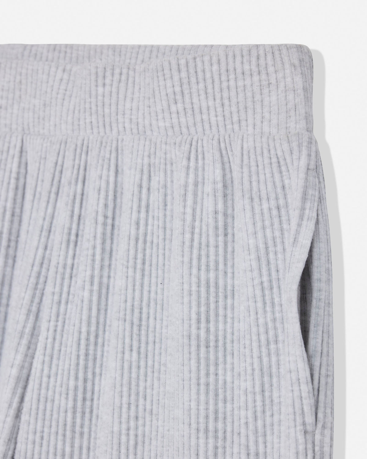 Close-up of a light gray ribbed knit fabric, showing the texture and waistband detail of a garment.