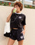 Person wearing a black sports outfit with white accents, drinking matcha.#color_black