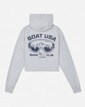 A light heather gray cropped hoodie shown from the back, featuring a dark navy graphic of ski goggles with a mountain scene inside, the text 'GOAT USA' above, and 'SNOW CLUB' below.