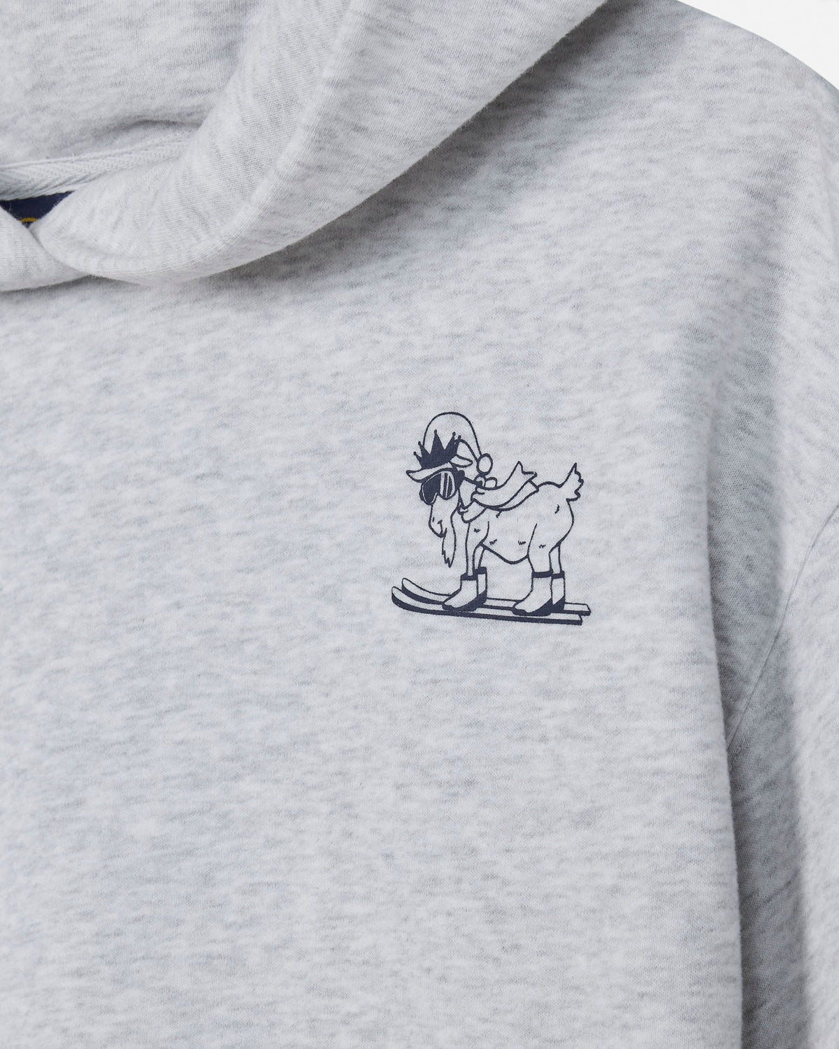 Close-up of a light heather gray hoodie featuring a small navy blue graphic of a cartoon goat skiing on the left chest.