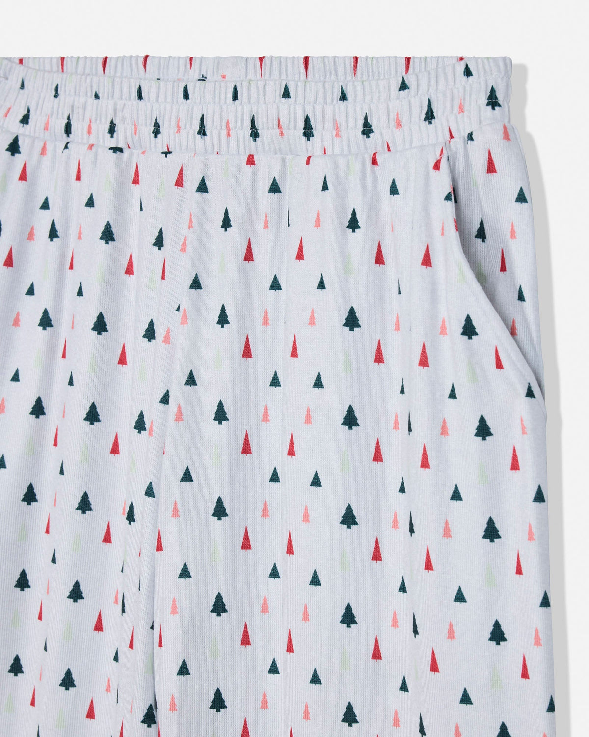 White elastic waistband shorts with an all-over pattern of small pine trees in dark green, red, and light pink, shown against a plain white background.