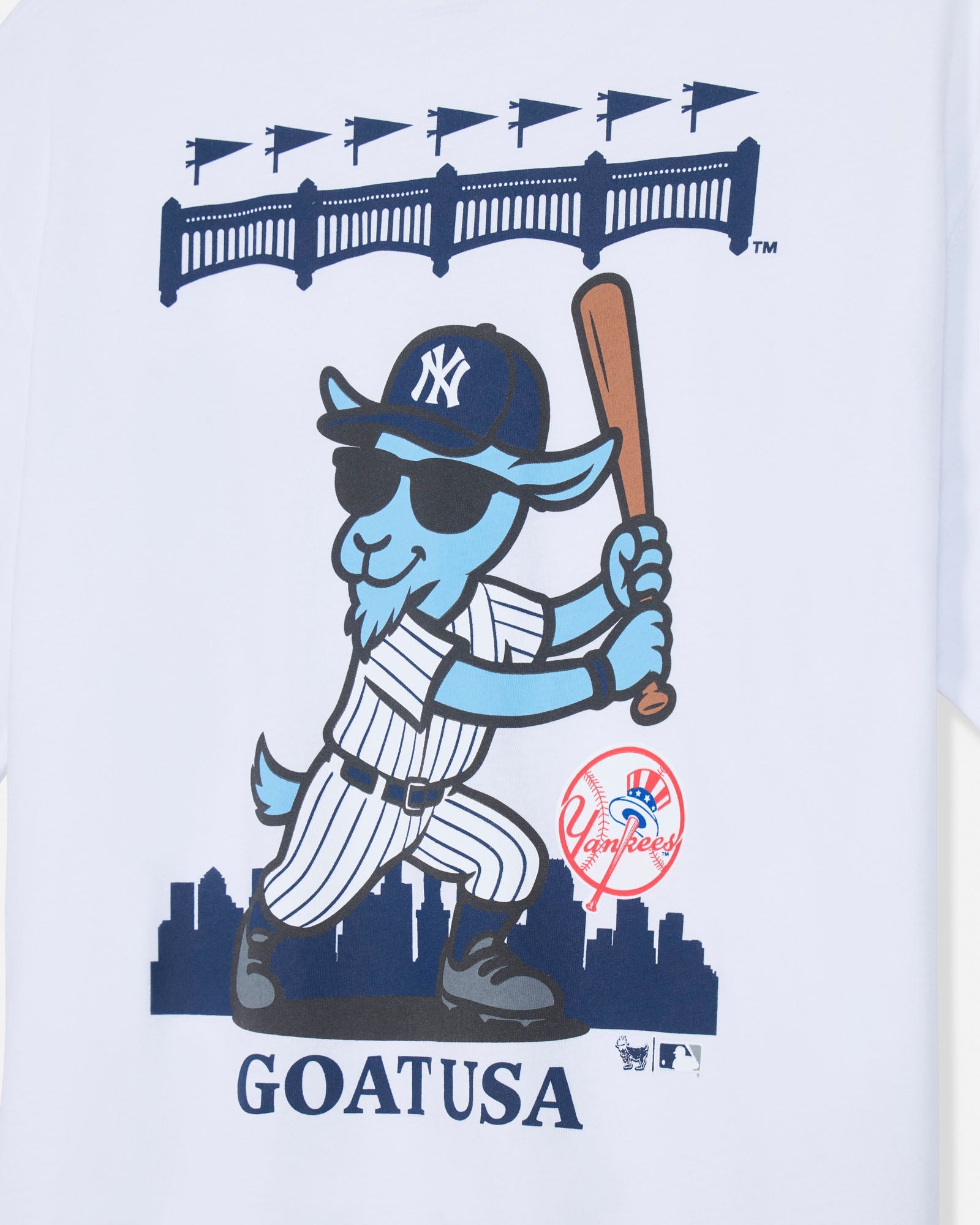 A close-up of a white graphic print featuring a cartoon blue goat in a New York Yankees baseball uniform, holding a bat, with the word 'GOAT USA' below and a red Yankees logo near the lower right of the character.#color_white