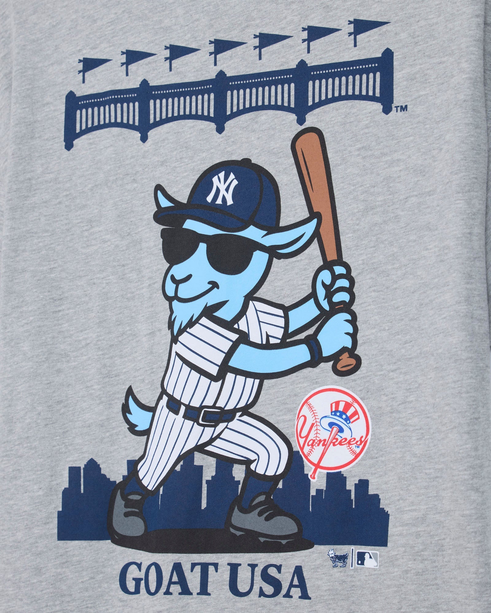 Close-up of a heather gray graphic print featuring a cartoon blue goat in a New York Yankees baseball uniform, holding a bat, with the text 'GOAT USA' and a Yankees logo.#color_gray