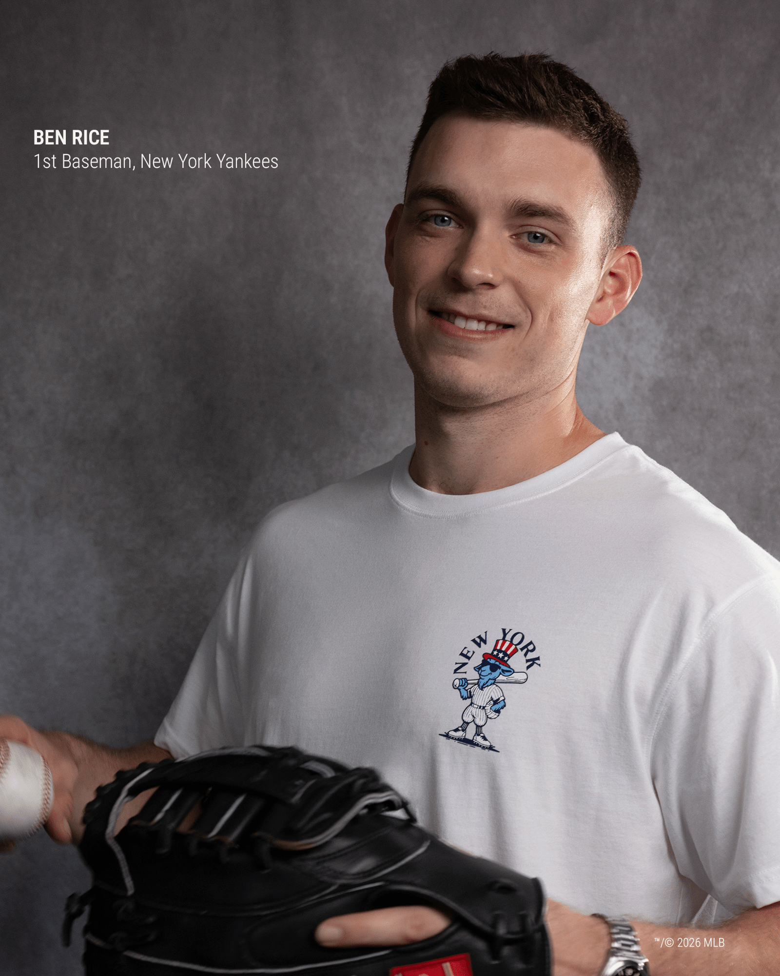A smiling man in a white New York Yankees graphic t-shirt holds a black baseball glove. The photo has a gray textured studio background, with text in the upper left identifying him as Ben Rice, 1st Baseman, New York Yankees.#color_white