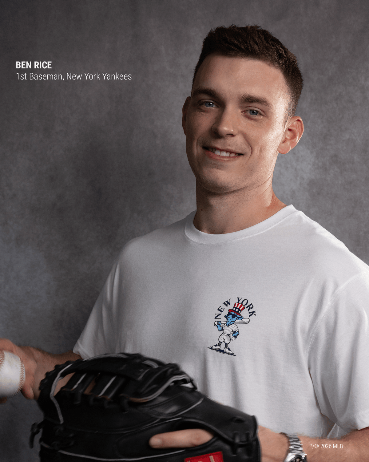 A smiling man in a white New York Yankees graphic t-shirt holds a black baseball glove. The photo has a gray textured studio background, with text in the upper left identifying him as Ben Rice, 1st Baseman, New York Yankees.